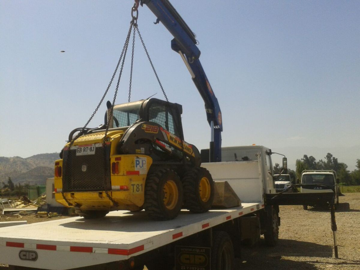 Minicargador siendo cargado en camión pluma